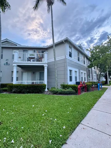 a view of a brick house with a big yard and large trees