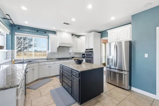 a kitchen with stainless steel appliances granite countertop a refrigerator a sink a stove a microwave and island