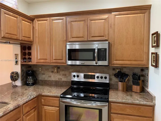 a kitchen with granite countertop a stove a sink and cabinets