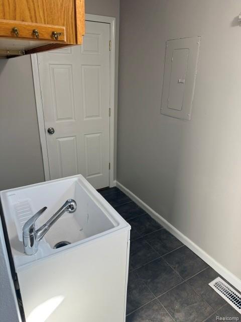 465 Trombley Road Troy, MI 48083 - Photo 19 of 24 Utility sink with chrome faucet, wood-finish upper cabinetry, gray wall paint, white interior door, and dark tile flooring