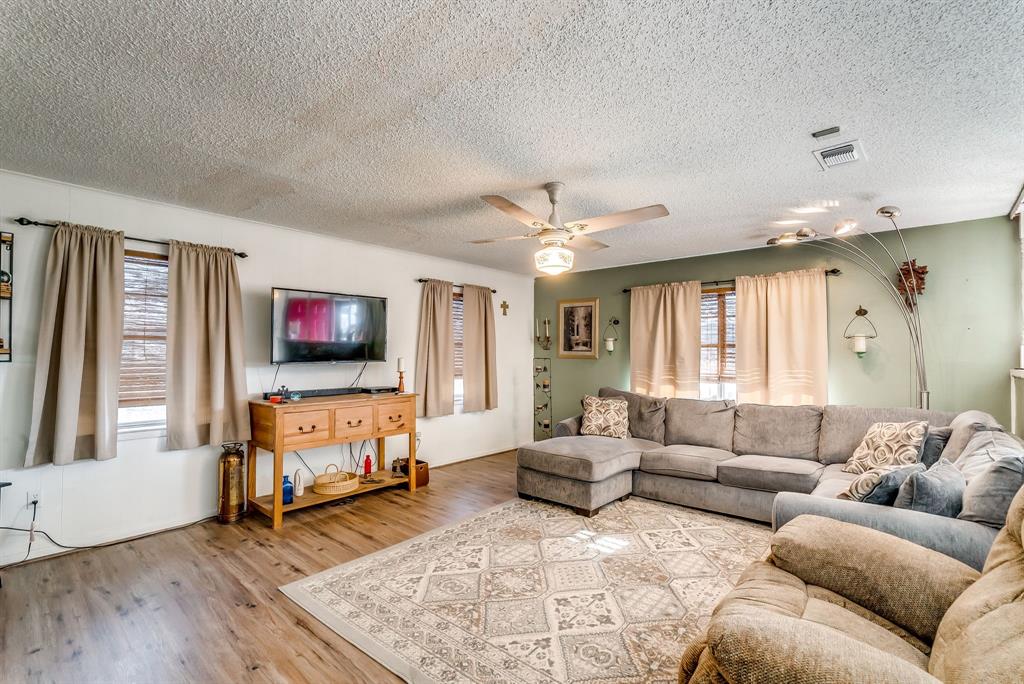 2912 Farm To Market 920 Weatherford, TX 76088 - Photo 11 of 28 Living room featuring a textured ceiling, wood finished floors, visible vents, and a ceiling fan