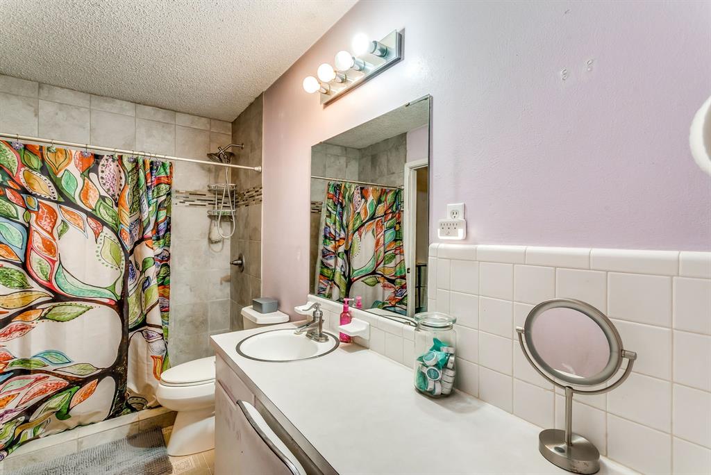 2912 Farm To Market 920 Weatherford, TX 76088 - Photo 16 of 28 Full bath with tile walls, toilet, a textured ceiling, vanity, and a shower with curtain