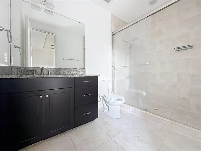 a bathroom with a granite countertop sink toilet and shower