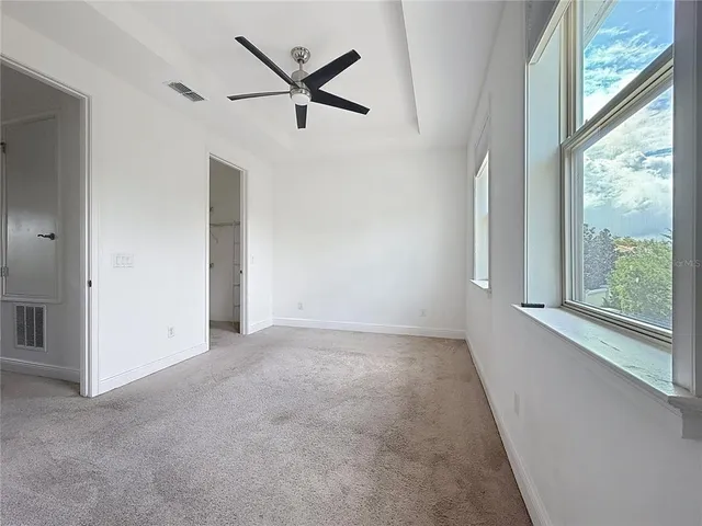 an empty room with windows and view of ceiling fan