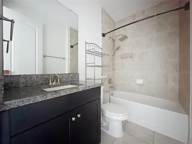 a bathroom with a granite countertop sink a toilet and shower