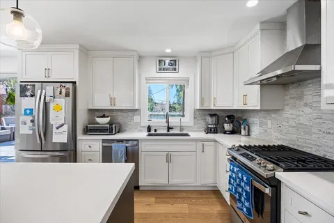 a kitchen with stainless steel appliances granite countertop a stove a sink dishwasher and a refrigerator