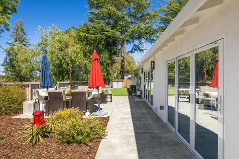 a view of a patio with table and chairs potted plants and large tree