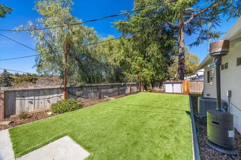 a view of a backyard with table and chairs potted plants and large tree