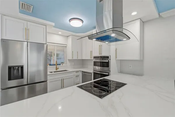 a kitchen with stainless steel appliances a sink a stove a refrigerator and cabinets