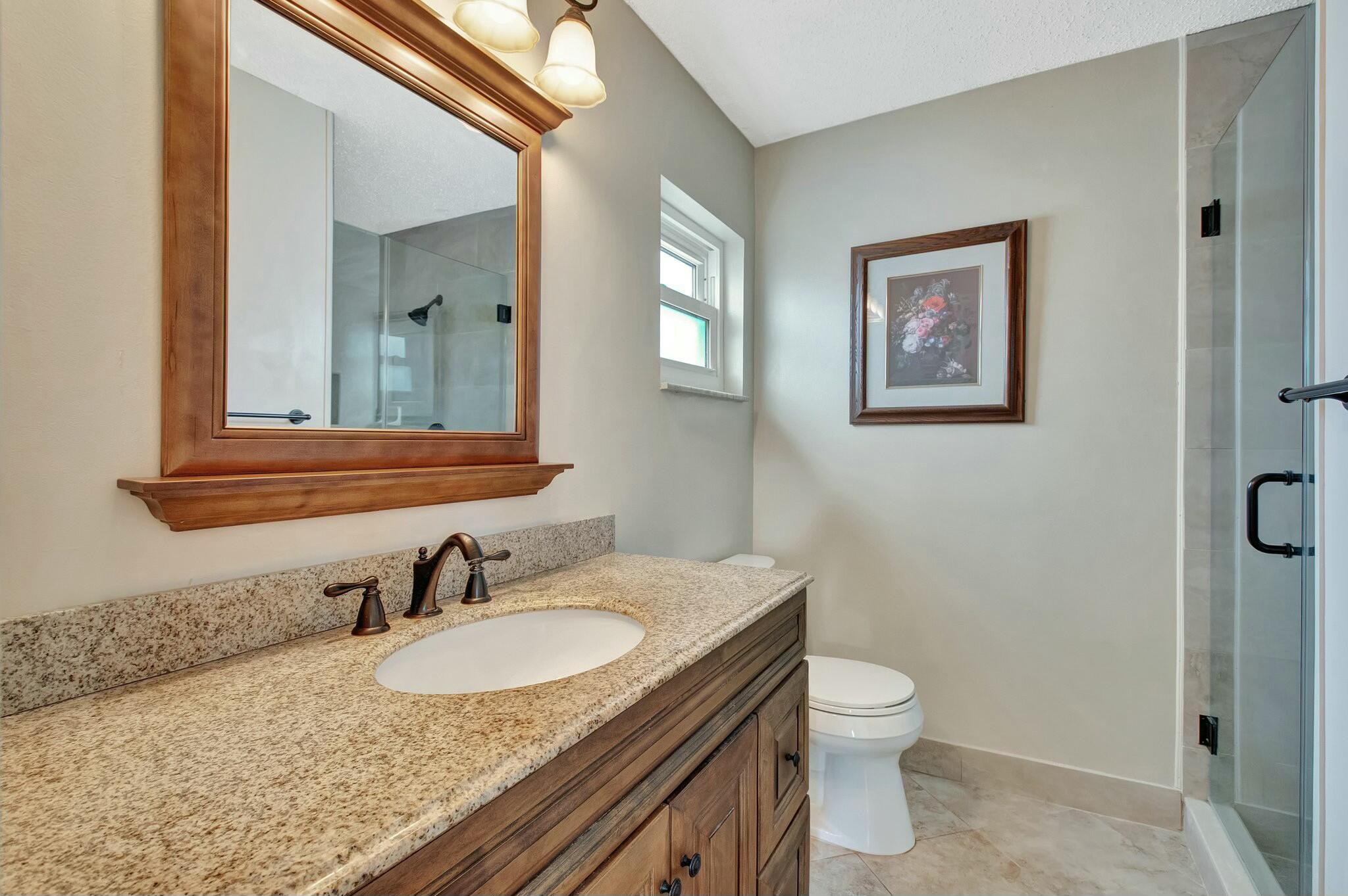 1704 Southwest 16th Street Boynton Beach, FL 33426 - Photo 26 of 44 a bathroom with a granite countertop sink vanity mirror and toilet
