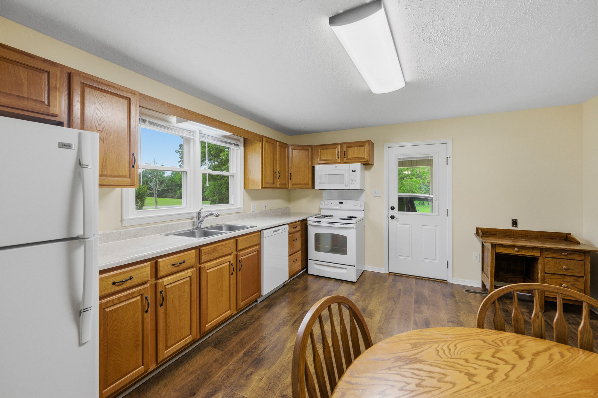 944 Brooksie Thompson Road Decaturville, TN 38329 - Photo 19 of 47 a kitchen with stainless steel appliances granite countertop a stove a refrigerator a sink a dining table and chairs with wooden floor