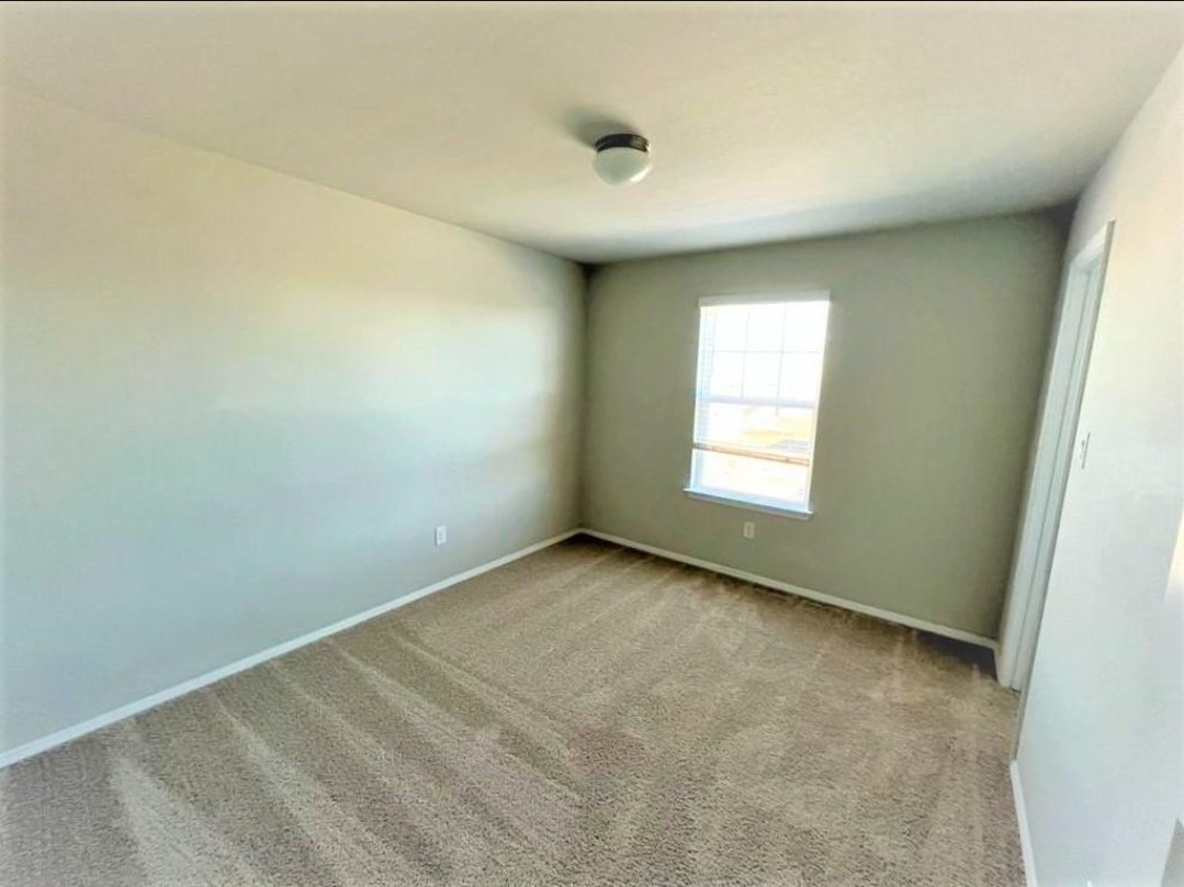2771 Winding Creek Road Kyle, TX 78640 - Photo 16 of 24 A well-lit bedroom with fresh carpet and a clear window offering exterior views.