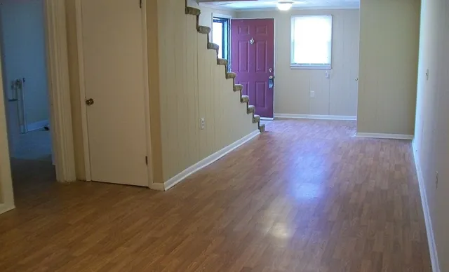 an empty room with wooden floor and windows