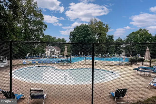 a swimming pool on a sunny day with lawn chairs