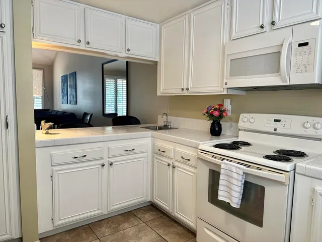 a kitchen with granite countertop white cabinets and white appliances