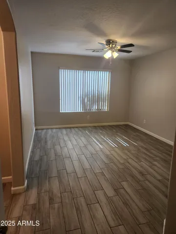 a view of an empty room with wooden floor and a window