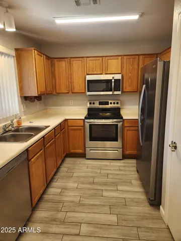 a kitchen with stainless steel appliances granite countertop a refrigerator a sink dishwasher a stove top oven and cabinets