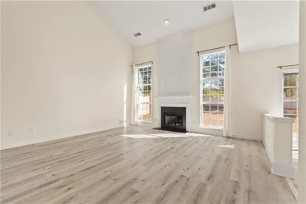 an empty room with wooden floor fireplace and windows