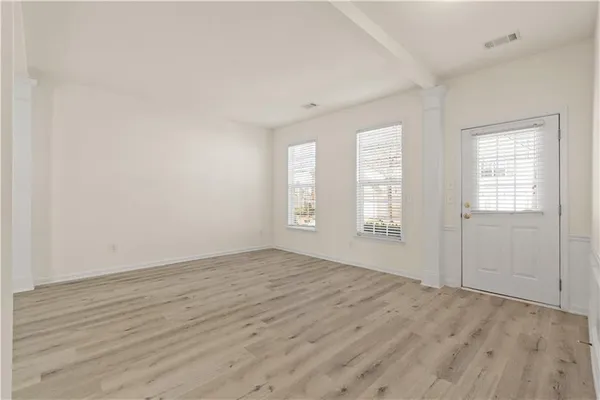 an empty room with wooden floor and windows