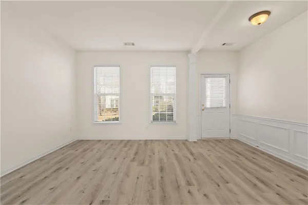 an empty room with wooden floor and windows