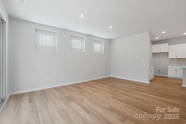 a view of empty room with wooden floor and window