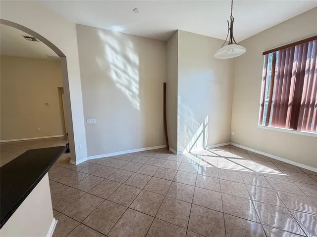 a view of an empty room with window and chandelier fan
