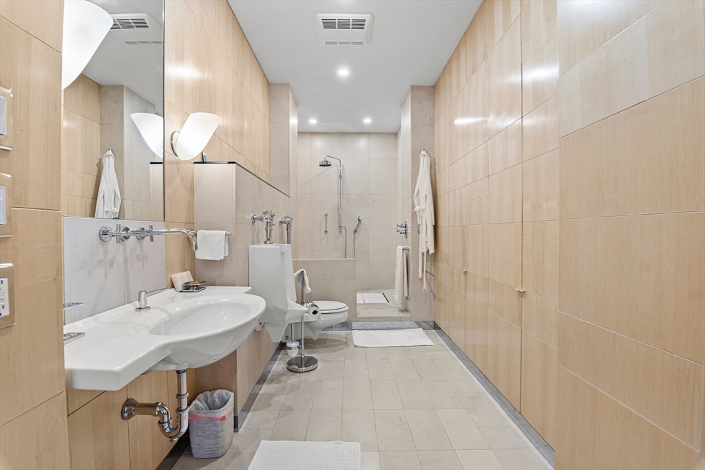 453 Washington Street, Unit 3A Boston, MA 02111 - Photo 13 of 18 a large bathroom with a sink a toilet a large mirror and shower