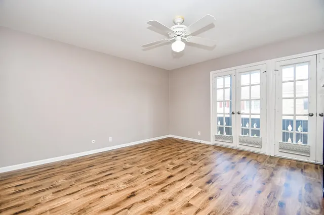 a view of an empty room with a window and wooden floor