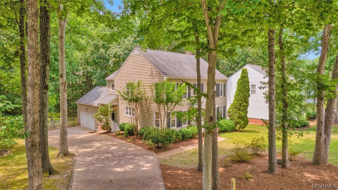 View of side of home featuring a double width shaded aggregate driveway that lead to oversized 2 car garage