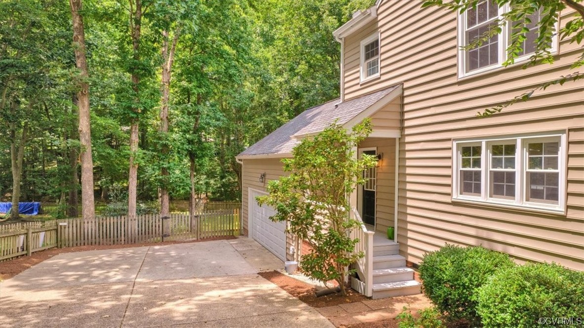 View of side of home featuring a double width shaded aggregate driveway that lead to oversized 2 car garage