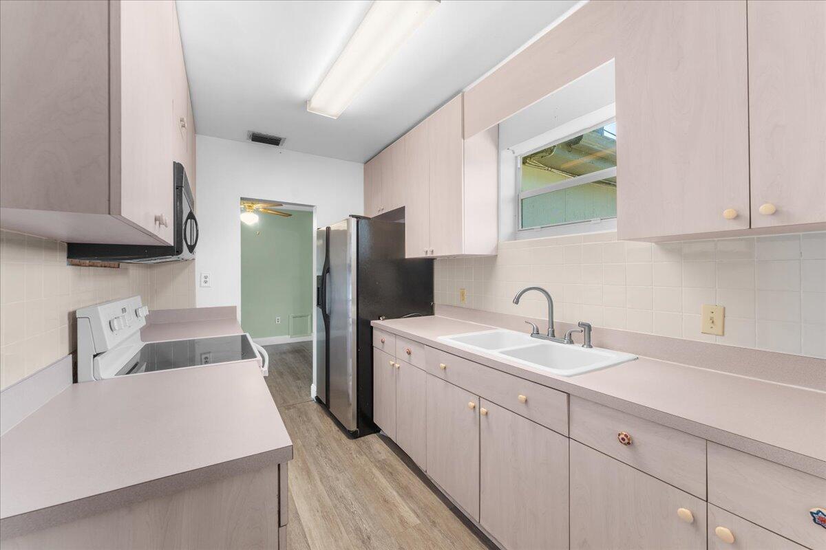 3308 Purdue Street Melbourne, FL 32901 - Photo 9 of 43 a kitchen with a sink a refrigerator a stove and a cabinets