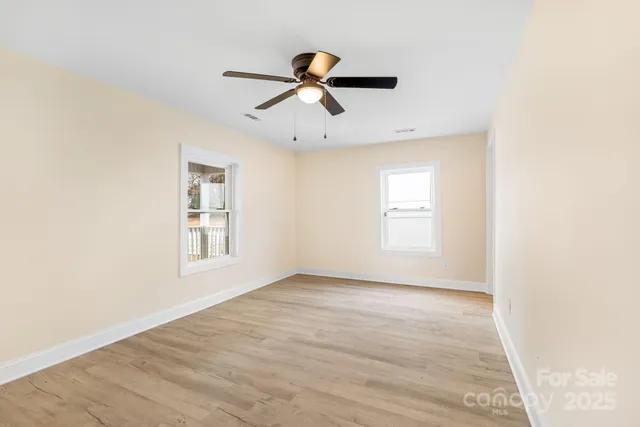 a view of empty room with wooden floor and window