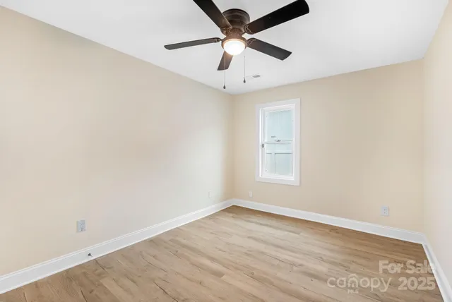 an empty room with a window and a fan