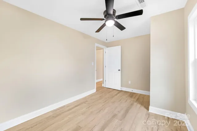 an empty room with a window and a fan