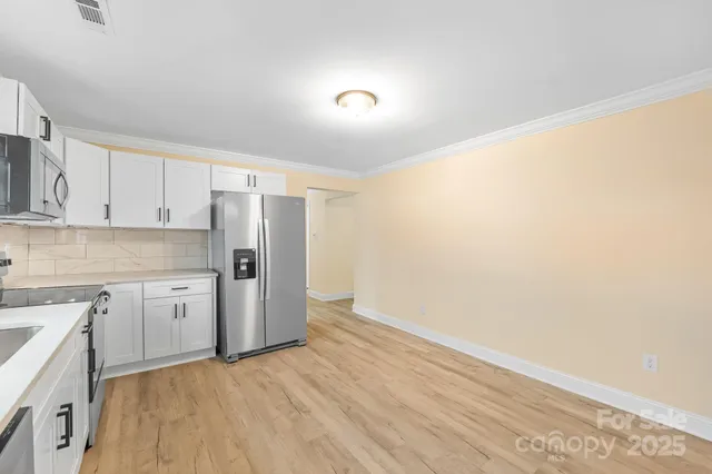 a kitchen with granite countertop white cabinets and refrigerator