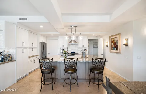 a dining hall with stainless steel appliances kitchen island granite countertop a table and chairs