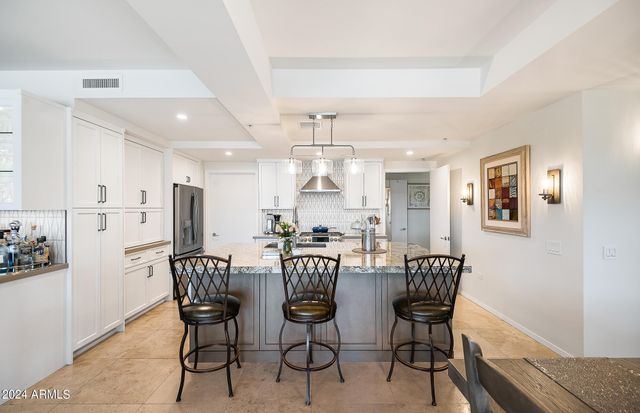 a dining hall with stainless steel appliances kitchen island granite countertop a table and chairs