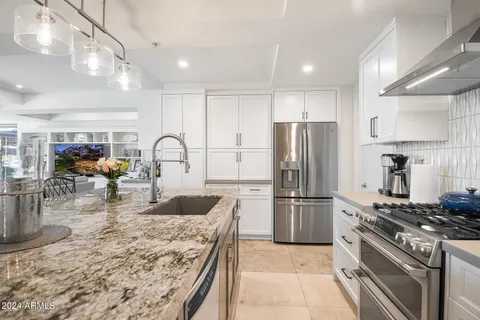 a kitchen with stainless steel appliances granite countertop a refrigerator and a stove top oven