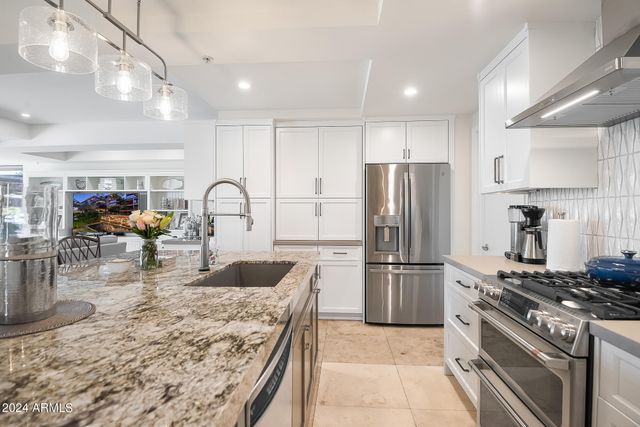 a kitchen with stainless steel appliances granite countertop a refrigerator and a stove top oven