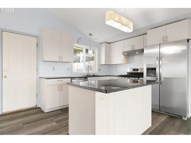 a kitchen with kitchen island a sink and a refrigerator