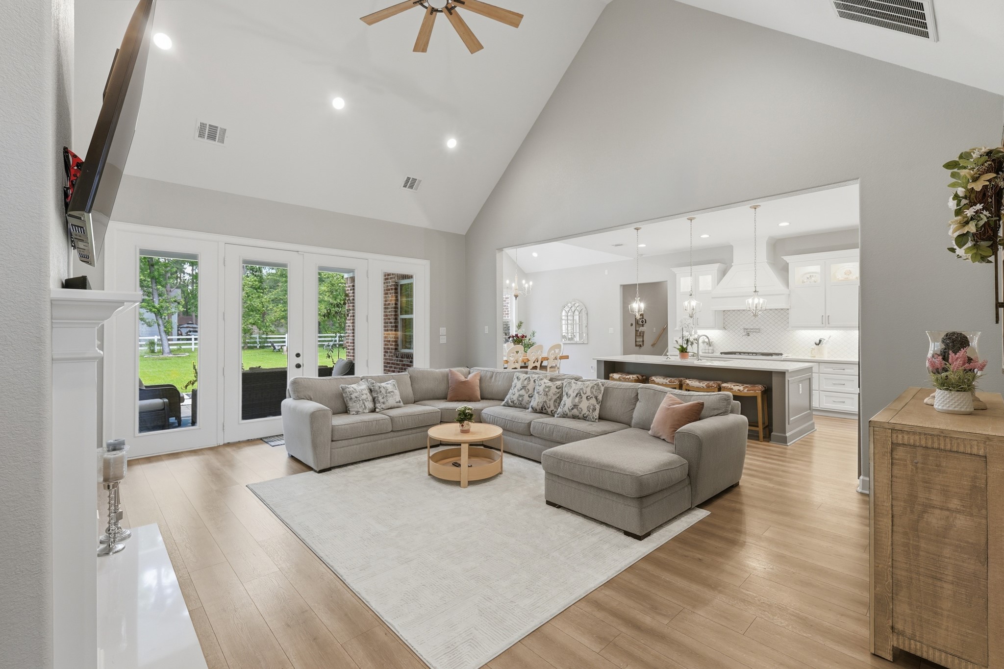 7106 Hampton Court Spring, TX 77389 - Photo 2 of 31 This inviting open-concept living space features high ceilings, a large sectional sofa, and abundant natural light from French doors leading to a lush backyard. The seamless flow into a modern kitchen with pendant lighting and an island makes it perfect for entertaining.