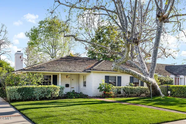 a front view of a house with a yard and potted plants