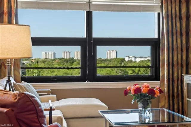a view of a dining room with furniture a potted plant and a window