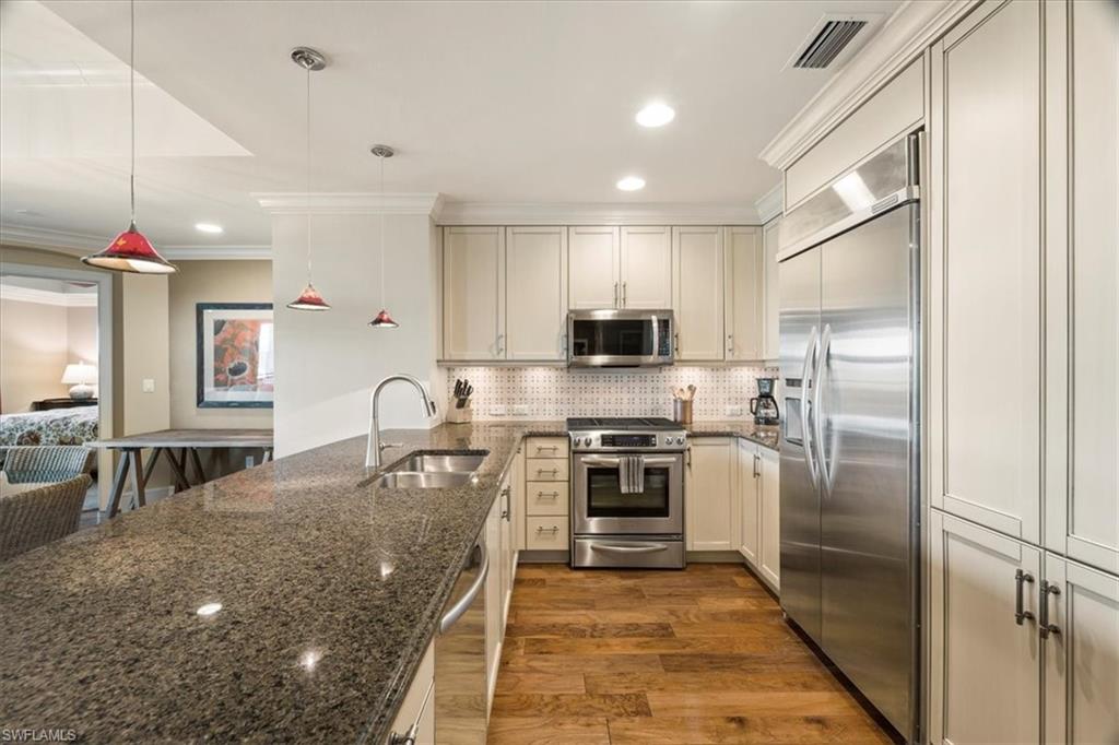 9115 Strada Place, Unit 5512 Naples, FL 34108 - Photo 9 of 42 a kitchen with kitchen island granite countertop lots of counter top space refrigerator and furniture