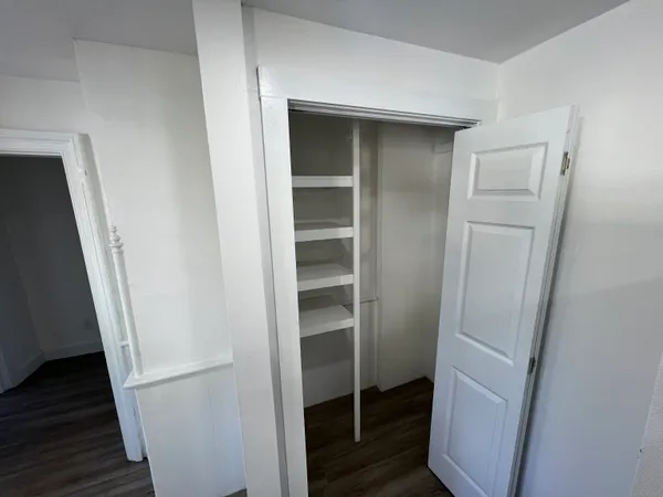a walk in closet with wooden floor