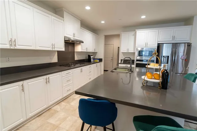 a kitchen with stainless steel appliances granite countertop a sink a stove and a refrigerator