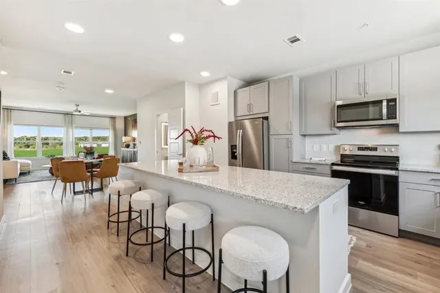 a large kitchen with a table chairs refrigerator and a wooden floor