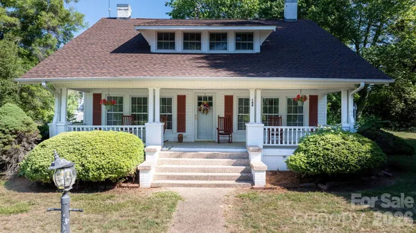 a view of a house with potted plants and a large tree