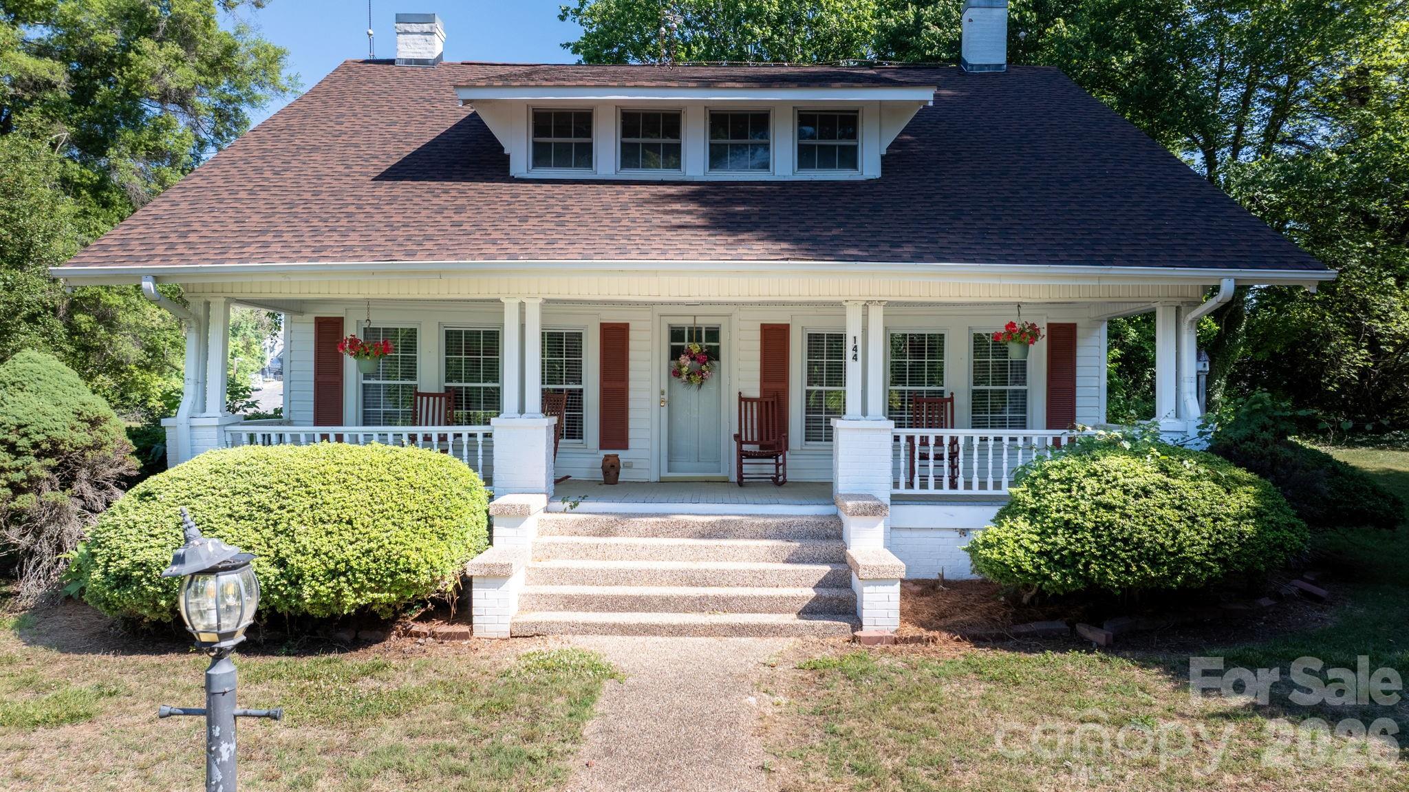 a view of a house with potted plants and a large tree