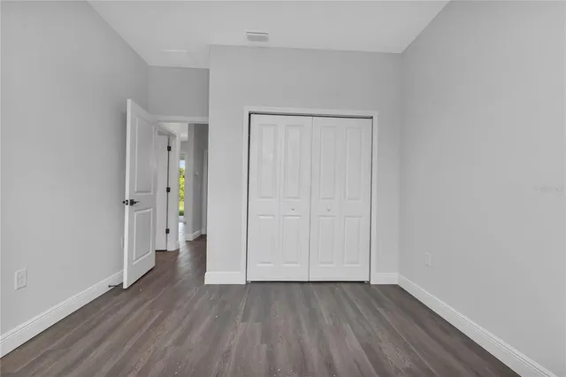 a view of an empty room with wooden floor and closet